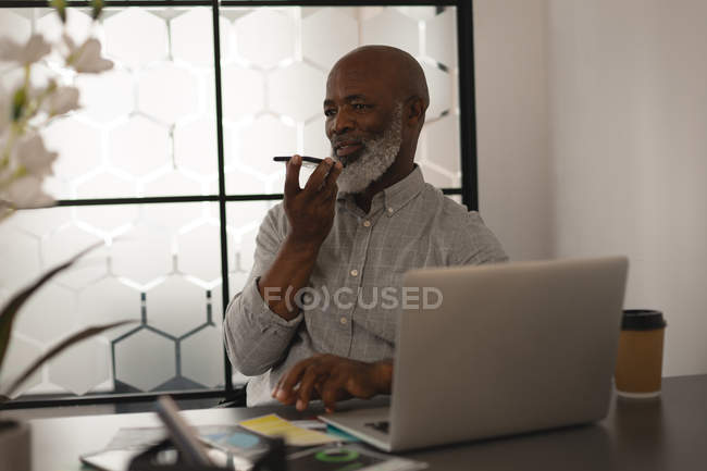 Старший графічний дизайнер розмовляє на мобільному телефоні за столом в офісі — стокове фото