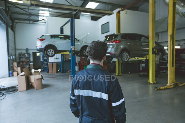 Rear view of mechanic standing in repair garage — Stock Photo