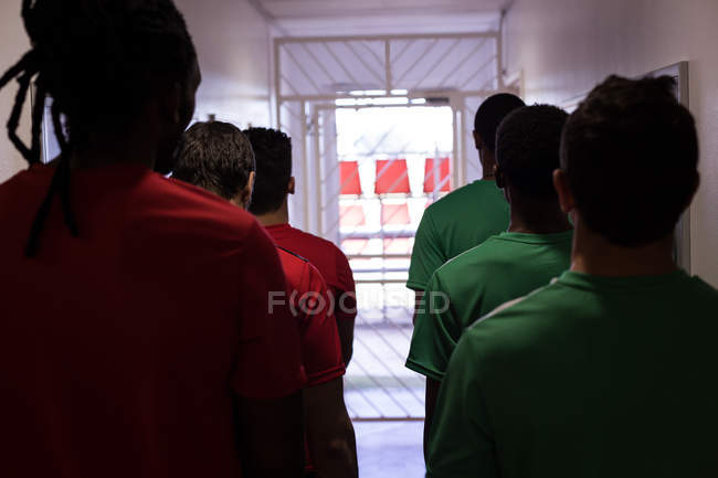 Vista trasera de los jugadores de fútbol que salen del vestidor - foto de stock