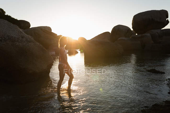 Mulher andando no mar na praia ao entardecer — Fotografia de Stock
