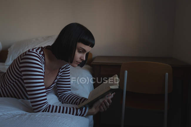Woman reading a book in bedroom at home — Stock Photo