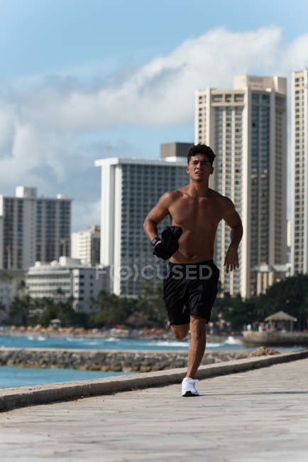 Молодой человек бегает около моря в солнечный день — стоковое фото