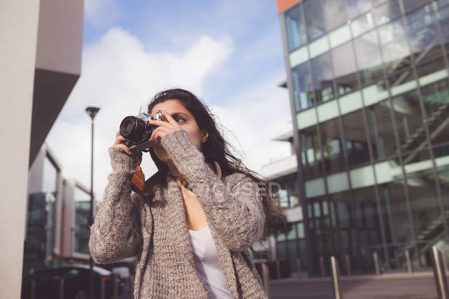 Mujer haciendo clic en la foto con cámara digital en la ciudad - foto de stock