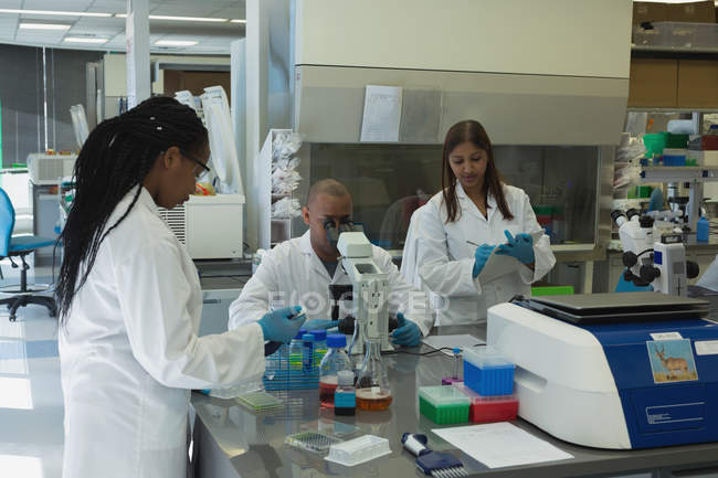 Científicos haciendo experimentos juntos en laboratorio - foto de stock