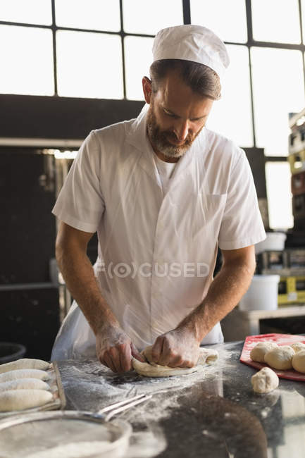 Maduro panadero macho preparando masa en panadería - foto de stock