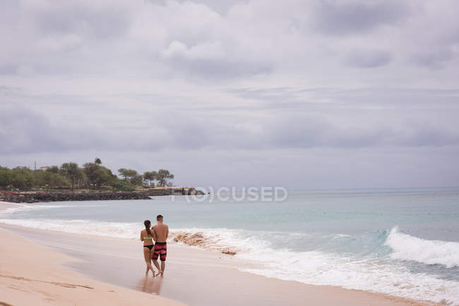 Coppia che cammina insieme in spiaggia in una giornata di sole — Foto stock