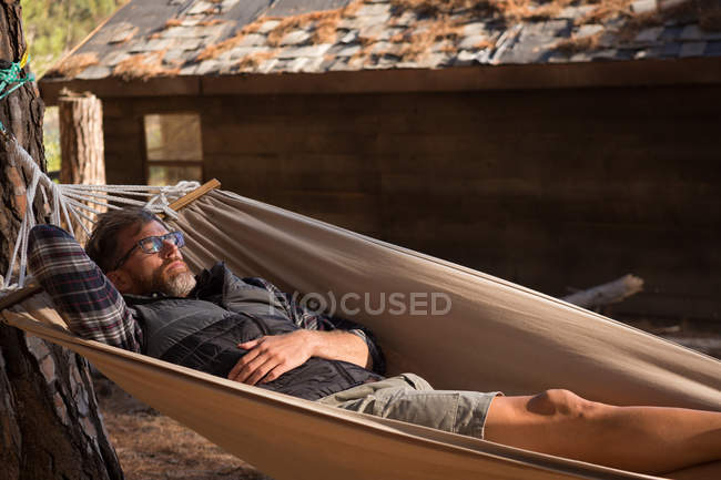 Homem relaxante em rede em um dia ensolarado — Fotografia de Stock