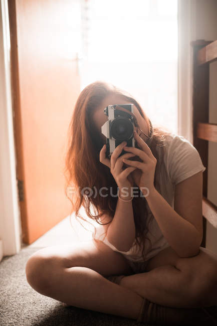Mujer haciendo clic en la foto con cámara en casa - foto de stock