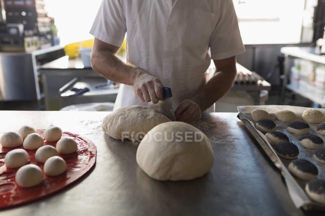 Sección media del panadero masculino que trabaja en la panadería - foto de stock