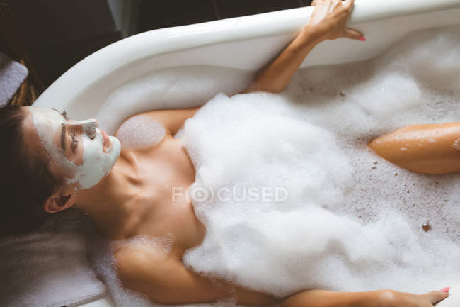 Mujer tomando un baño de burbujas en el baño en casa - foto de stock