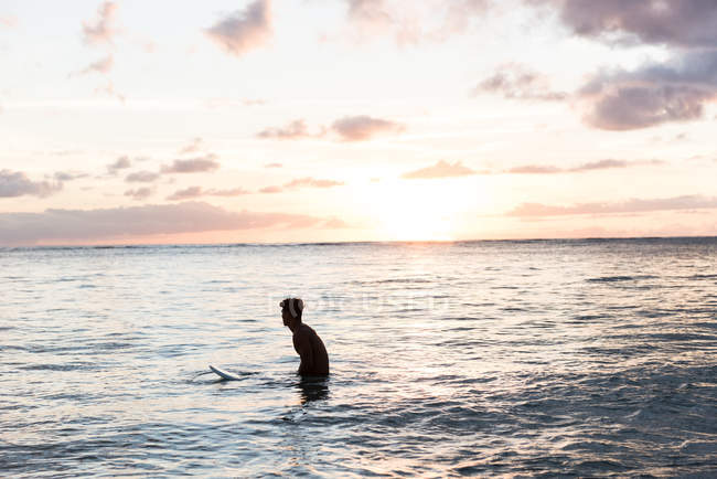 Surfista di sesso maschile che pratica surf con tavola da surf al tramonto — Foto stock