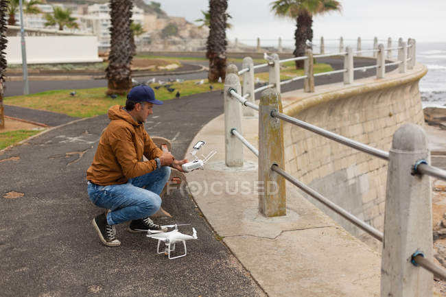 Uomo che aziona un drone volante vicino al marciapiede — Foto stock