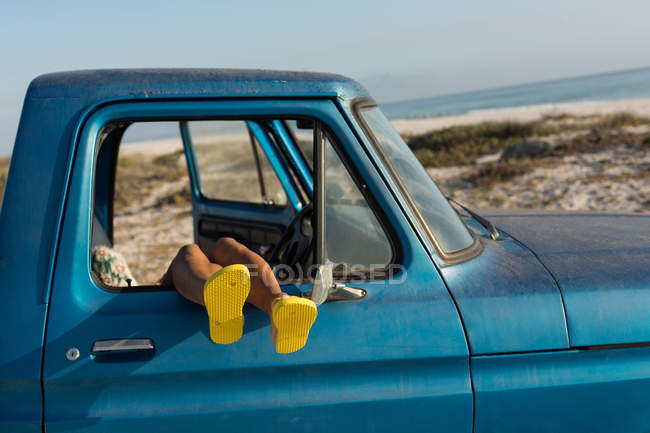 Frau entspannt sich mit den Füßen im Pickup am Strand — Stockfoto