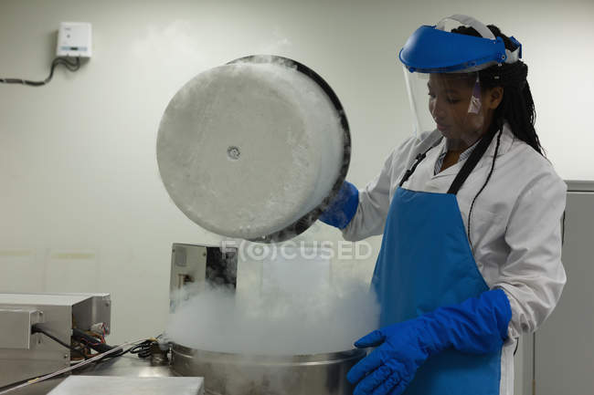 Female scientist opening lid of machine in lab — Stock Photo