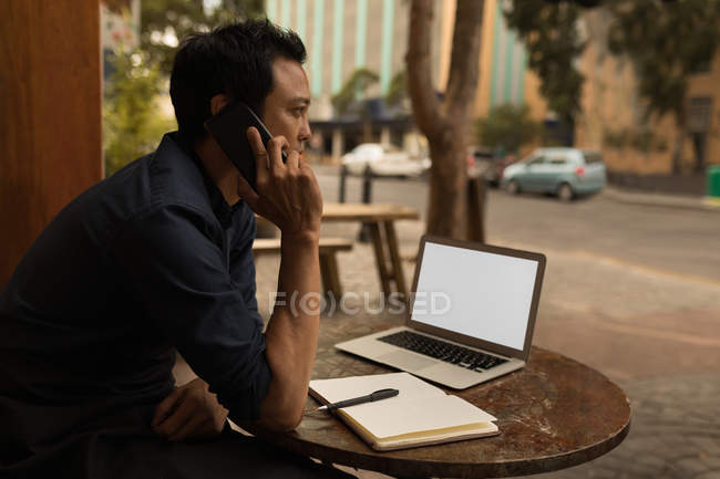 Вид збоку бізнесмена, що розмовляє на мобільному телефоні в кафе — стокове фото