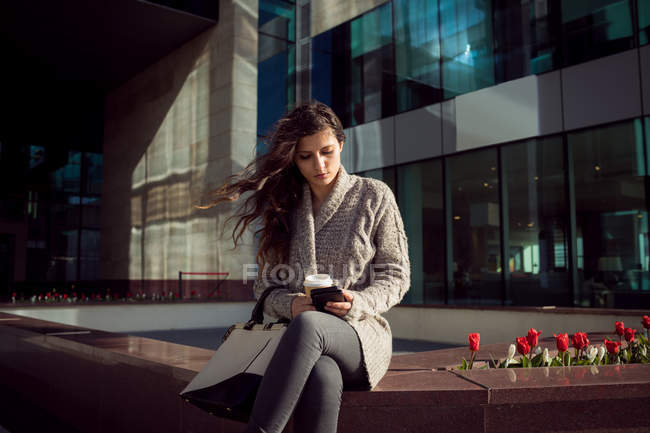 Молода жінка використовує мобільний телефон у місті — стокове фото
