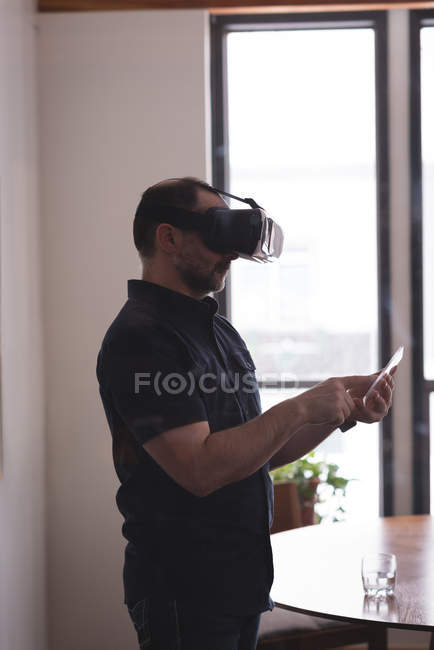 Чоловічий виконавчий за допомогою віртуальної реальності гарнітура з цифровий планшетний скла в офісі — стокове фото