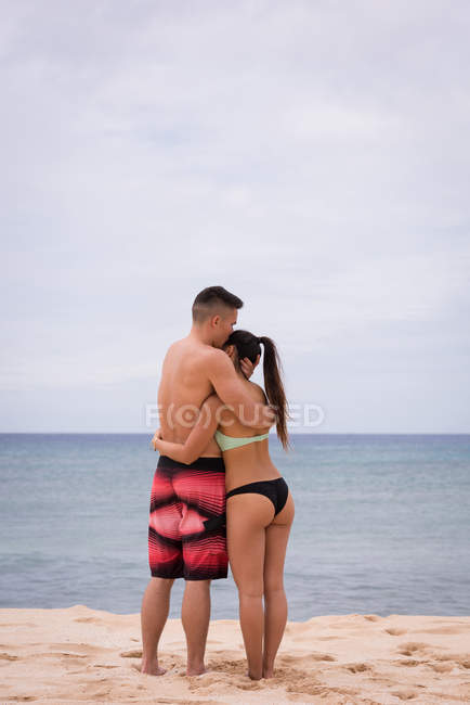 Rückansicht von Pärchen, die sich am Strand umarmen — Stockfoto
