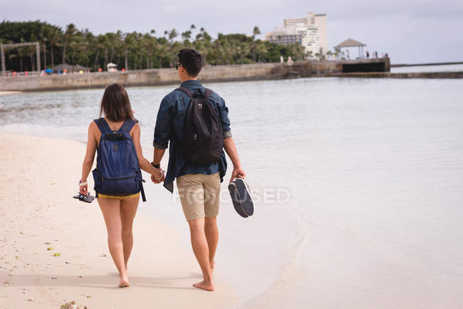 Вид сзади пары, гуляющей вместе на пляже — стоковое фото
