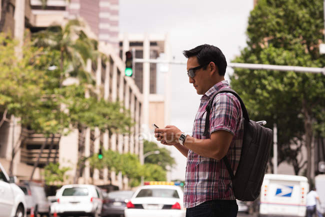 Smart man using mobile phone in city street — Stock Photo