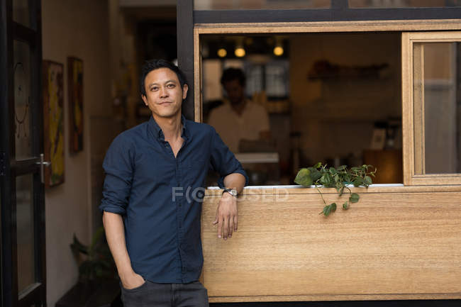 Улыбающийся бизнесмен стоит у окна в кафе — стоковое фото