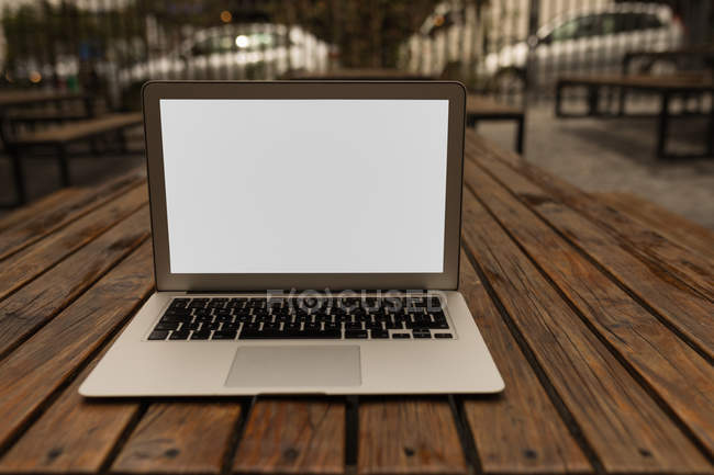 Laptop na mesa de madeira no café do pavimento — Fotografia de Stock