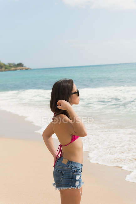 Frau steht an einem sonnigen Tag am Strand — Stockfoto