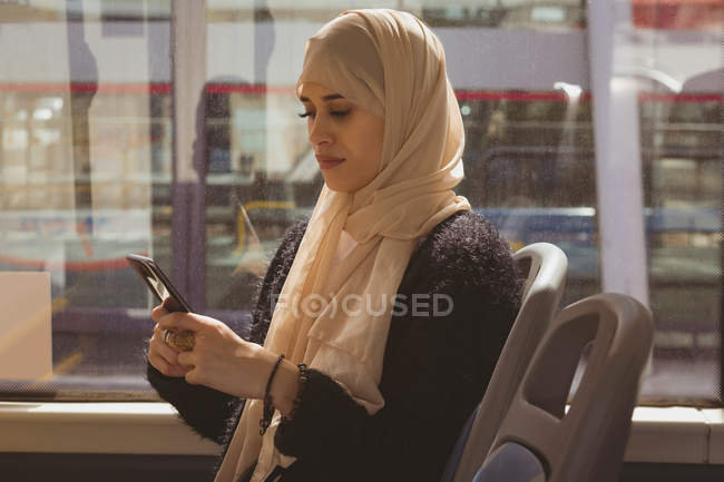 Belle femme hijab utilisant le téléphone portable tout en voyageant dans le bus — Photo de stock