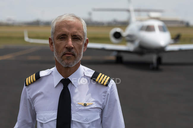 Portrait of senior male pilot standing on a runaway — Stock Photo