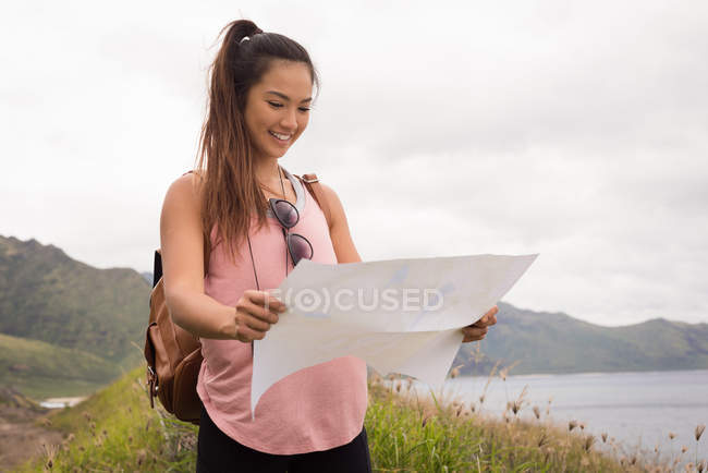Hermosa mujer mirando el mapa en el campo - foto de stock