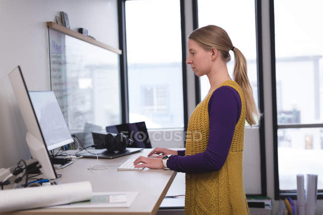Жінка-виконавця, що працює на комп'ютері за столом в офісі — стокове фото