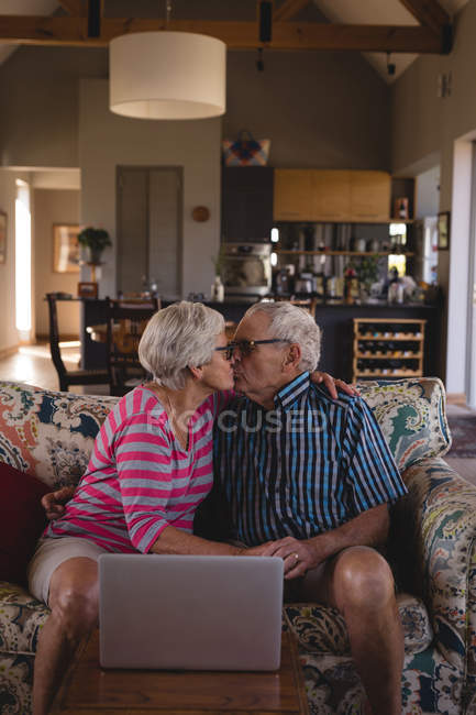 Романтична старша пара цілує один одного у вітальні вдома — стокове фото