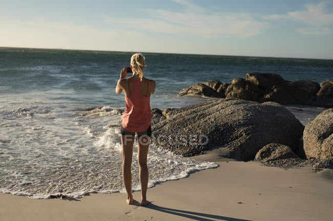 Joueuse de volley-ball prenant des photos avec téléphone portable sur la plage — Photo de stock