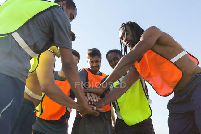 Счастливая футбольная команда держит друг друга за руки перед игрой — стоковое фото