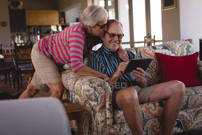 Pareja mayor usando tableta digital en la sala de estar en casa - foto de stock