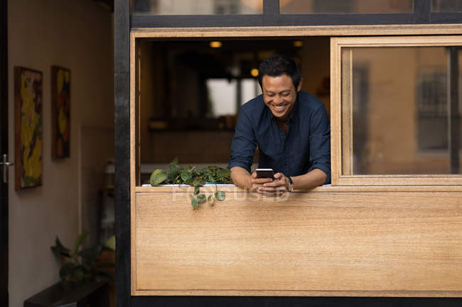 Empresário sorrindo usando telefone celular no café — Fotografia de Stock