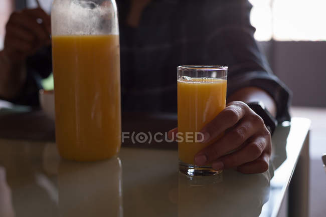 Mid section of man having orange juice at home — Stock Photo