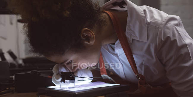 Female photographer using pocket magnifier in photo studio — Stock Photo