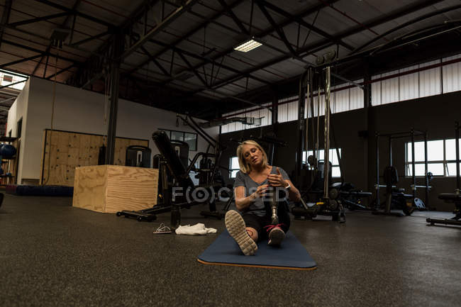 Behinderte reife Frau mit Beinprothese im Fitnessstudio — Stockfoto