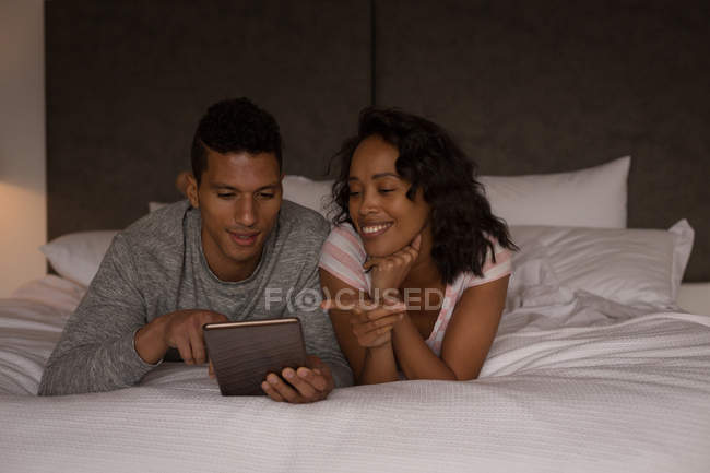 Couple using digital tablet in bedroom at home — Stock Photo