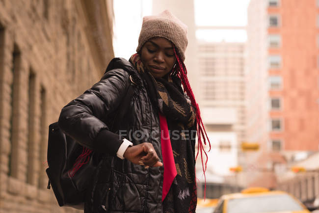Mulher verificando o tempo no relógio inteligente na rua da cidade — Fotografia de Stock