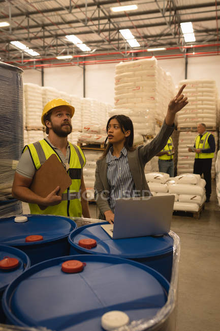 Personnel interagissant les uns avec les autres sur ordinateur portable dans l'entrepôt — Photo de stock