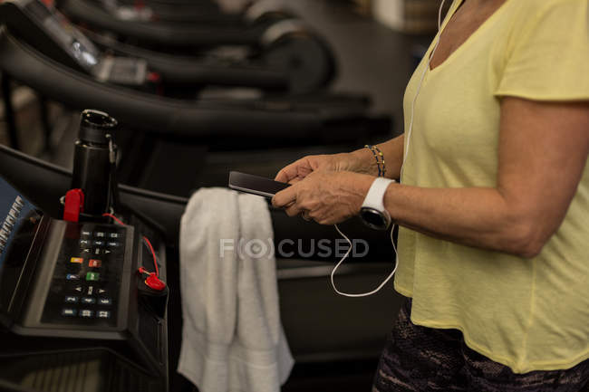Mulher com deficiência usando telefone celular durante o exercício em uma esteira — Fotografia de Stock