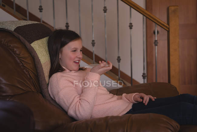 Дівчина розмовляє скляним мобільним телефоном у вітальні вдома — стокове фото