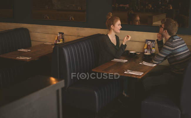 Pareja joven hablando entre sí en el restaurante - foto de stock