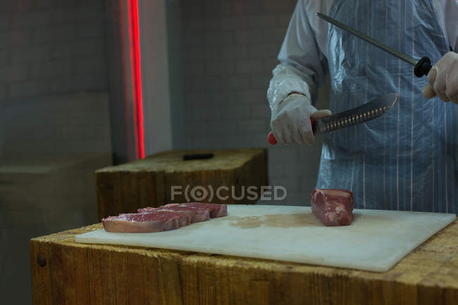 М'ясника, стоячи з шматок м'яса в м'ясний магазин — стокове фото