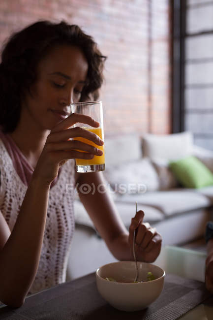 Woman having orange juice with breakfast at home — Stock Photo