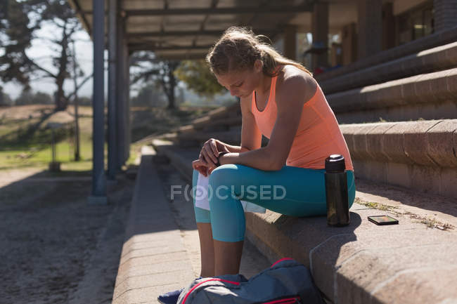 Athlète féminine utilisant smartwatch sur le site de sport — Photo de stock