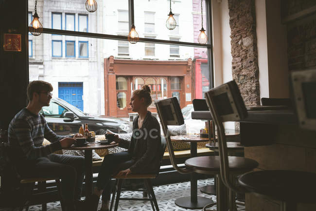 Couple interagissant les uns avec les autres tout en prenant un café dans le café — Photo de stock