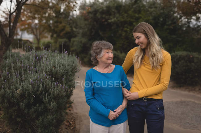 Granddaughter and grandmother walking on pavement during daytime — Stock Photo